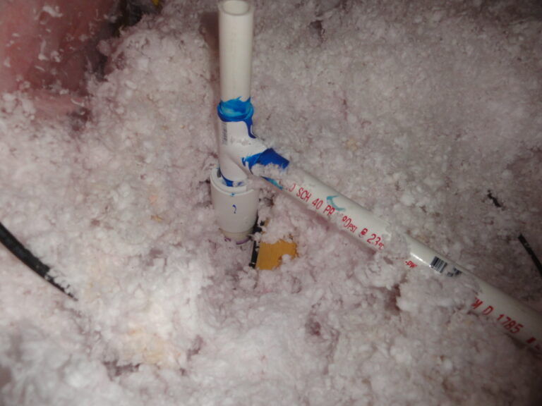 A PVC pipe with a blue valve surrounded by fluffy insulation material.