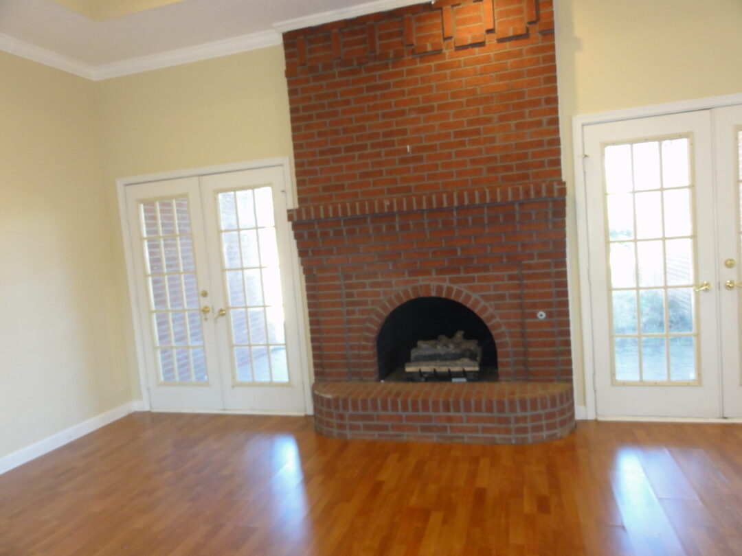 Cozy room with a brick fireplace and wooden floors.