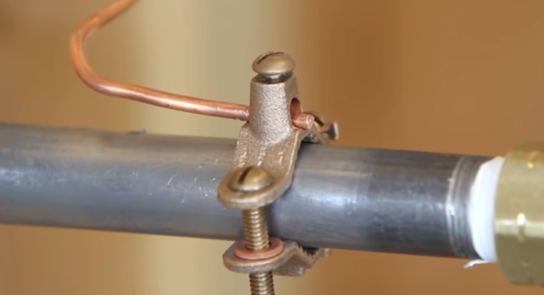 Close-up of a copper pipe clamp securing a pipe.