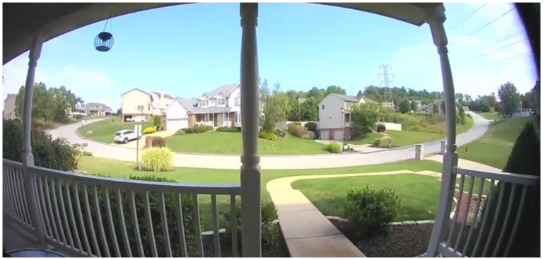 View of a suburban neighborhood from a porch with houses and greenery.