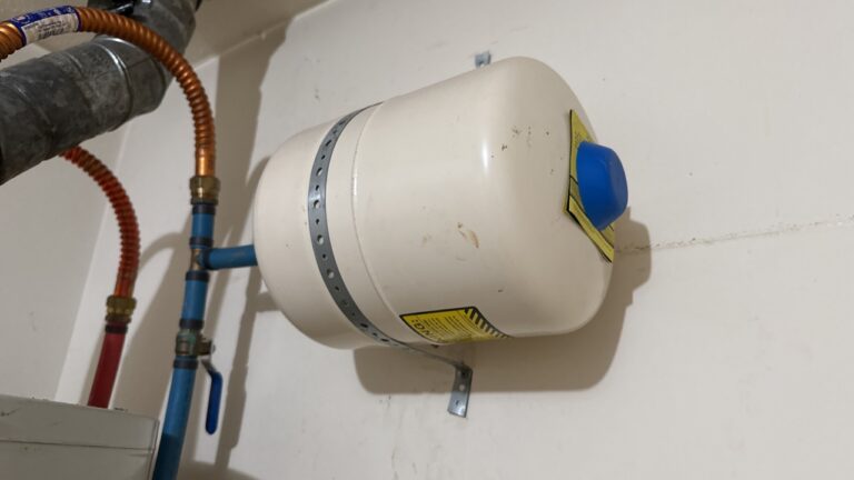 Horizontal thermal expansion tank mounted above a water heater on the cold-water supply piping
