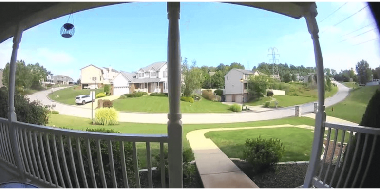 View of a suburban neighborhood from a porch with houses and greenery.