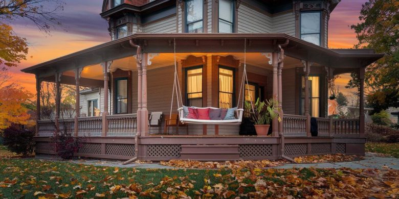 Cozy porch swing with cushions on a Victorian-style house at dusk.