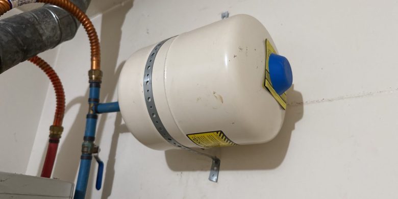 Horizontal thermal expansion tank mounted above a water heater on the cold-water supply piping